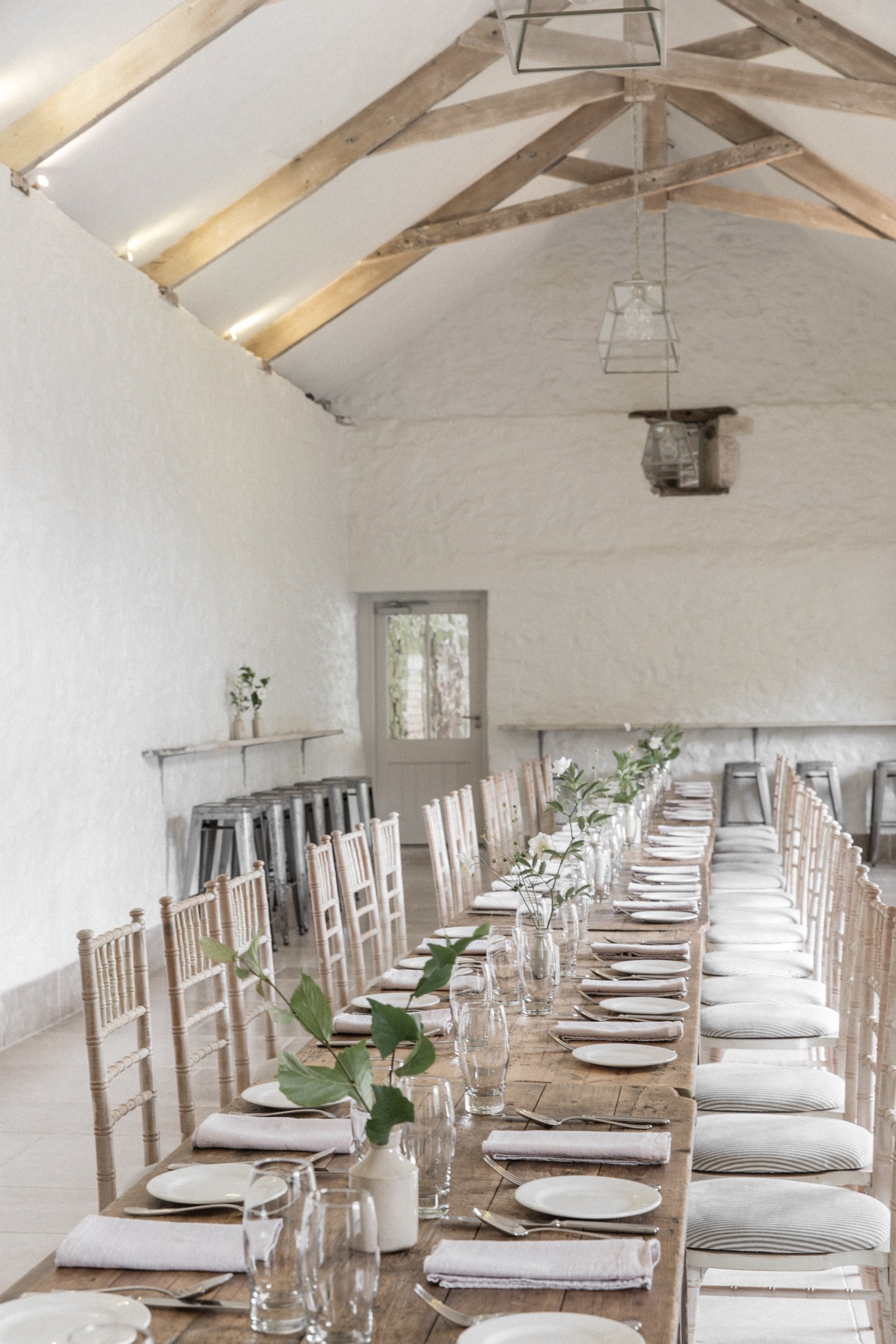 The Interior of The West Barn at The Great Barn Devon with a table laid out for guests to enjoy a friday night supper or a Sunday morning breakfast together during wedding weekend 