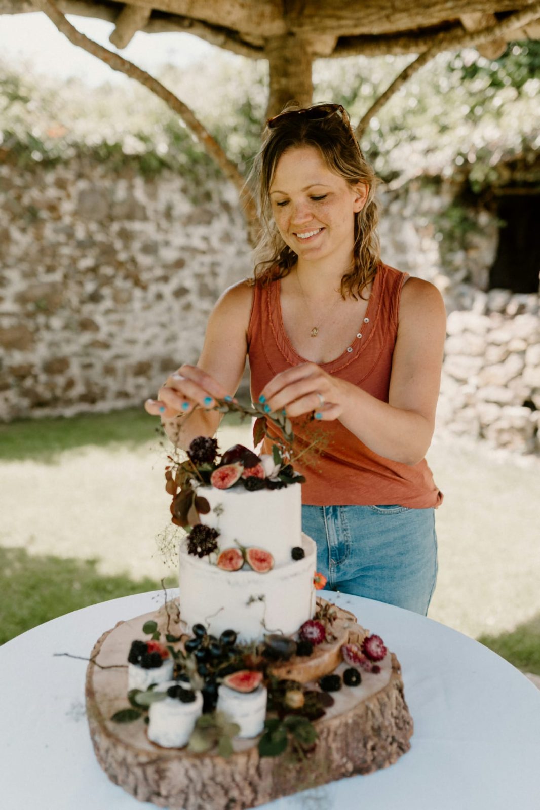 Nicole of Sweet Satisfaction cake design perfecting a wedding cake in the gardens of The Great Barn Devon a luxury wedding venue