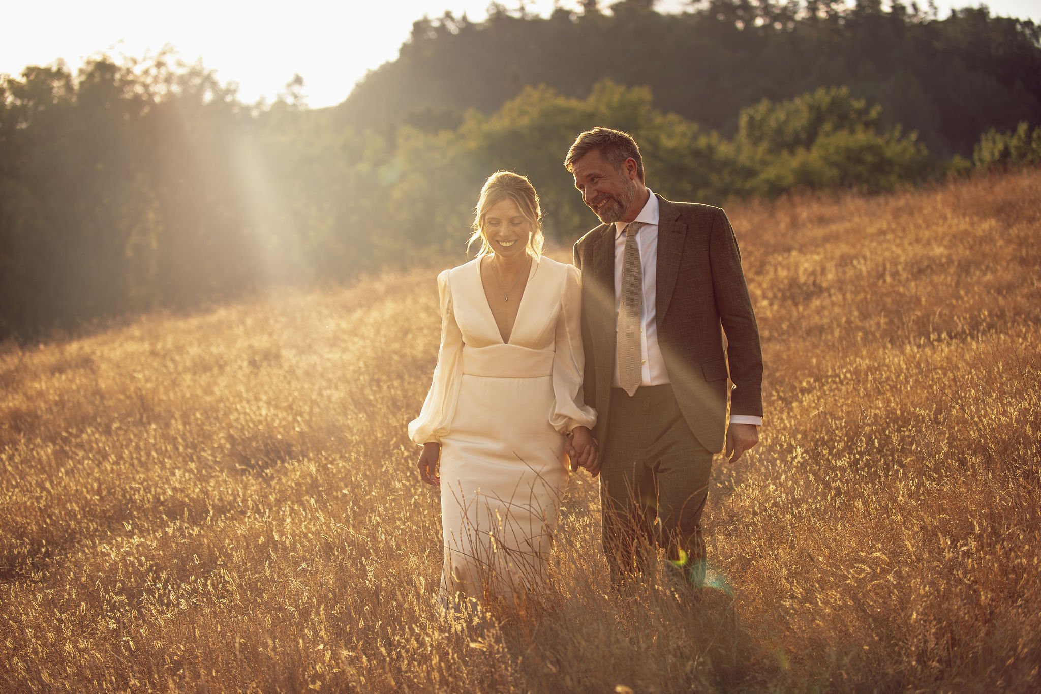 couple newlywed bride groom walk through corn field grass field the great barn devon wedding venue