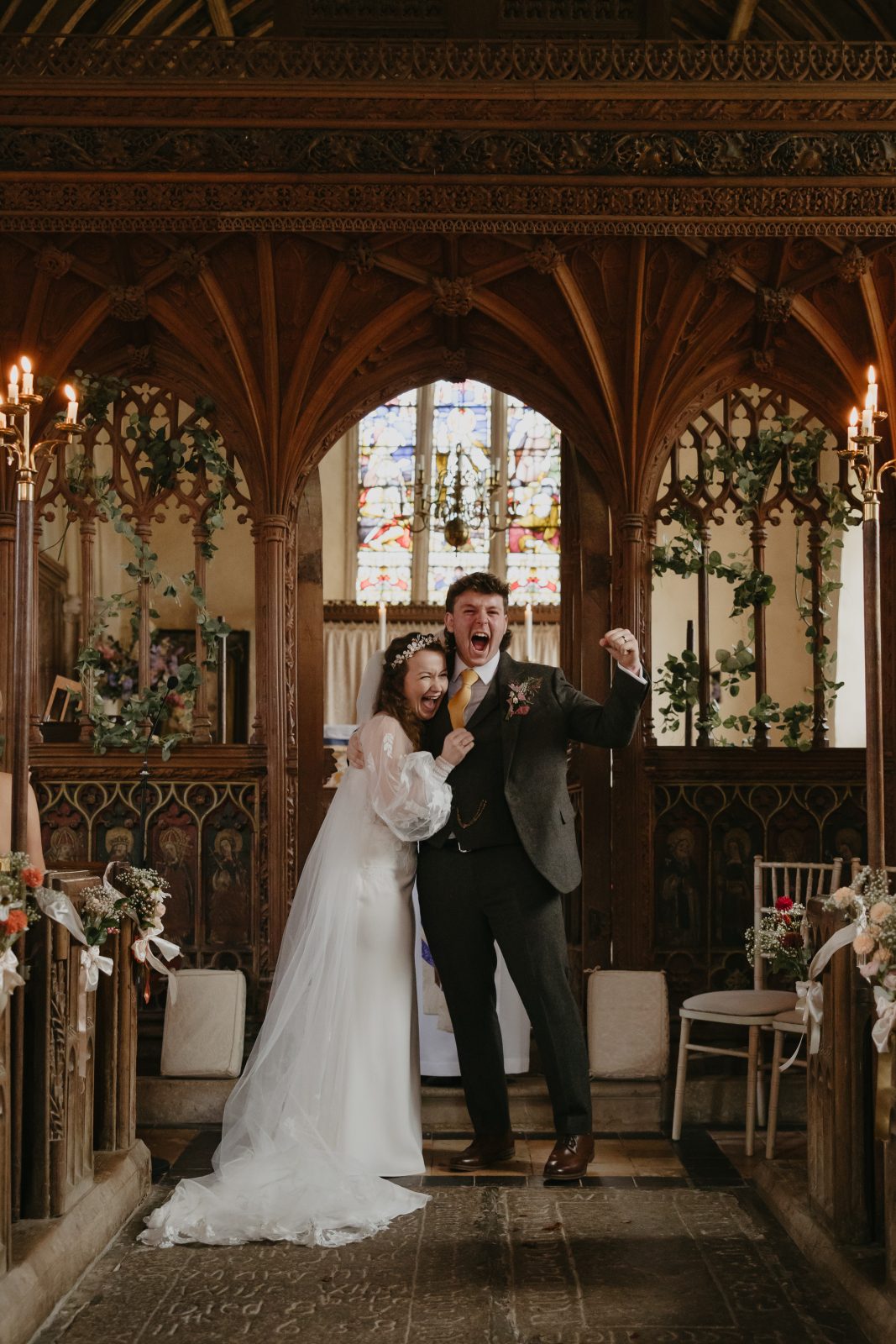a bride and groom stood at the alter at their church wedding before their wedding reception at the great barn devon